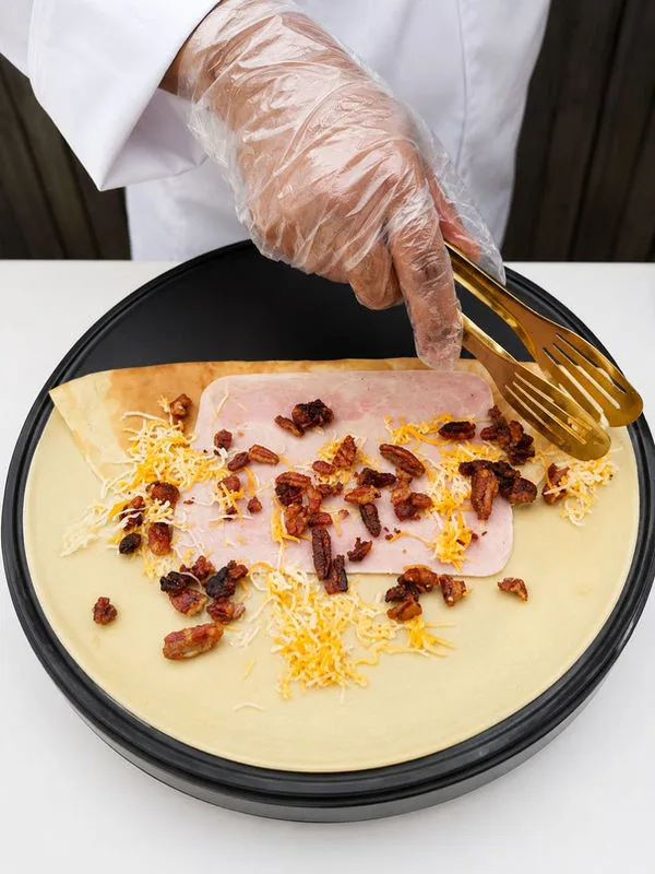 Caterer folding a warm crepe with sweet toppings